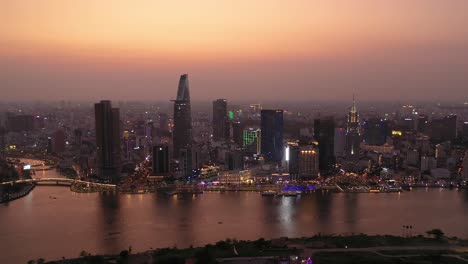 Ho-Chi-Minh-City,-Vietnam-iconic-Skyline-and-Saigon-river-waterfront-aerial-panorama-on-a-busy-evening-featuring-all-key-buildings-illuminated-against-beautiful-colored-sky