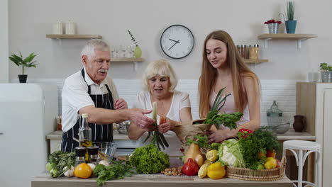 senior couple in kitchen receiving vegetables from granddaughter. healthy raw food nutrition