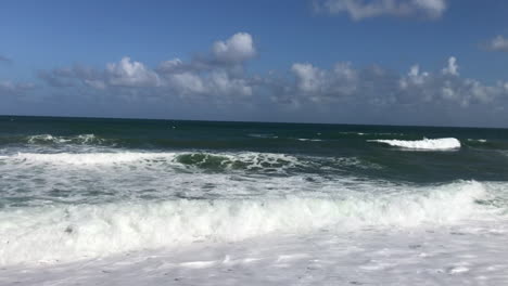 Rodando-Olas-Rompiendo-En-Una-Orilla-Arenosa-Con-Cocoteros