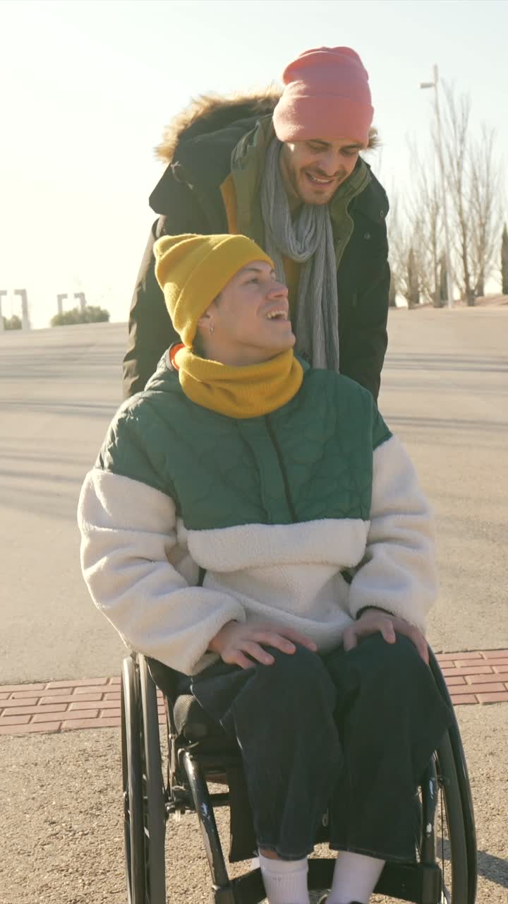 Man pushing friend in wheelchair in winter park