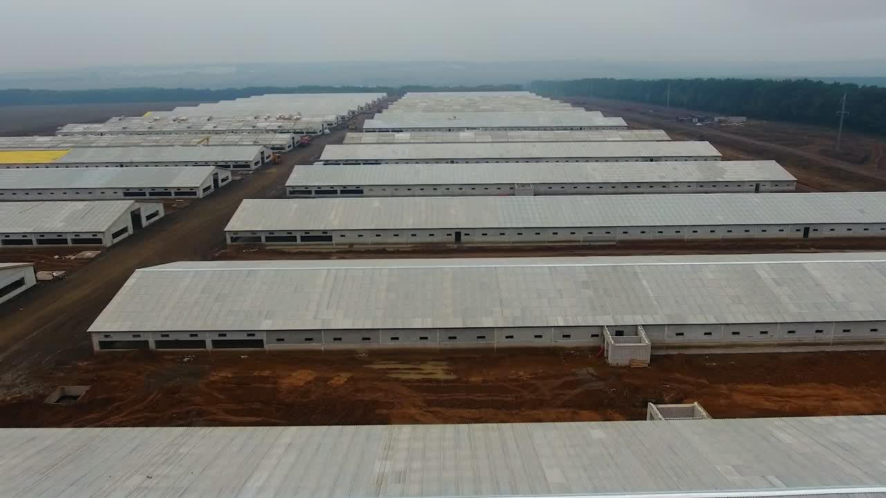 Modern animal farm building. Long hangars in the farm. White roofs of new industrial buildings.