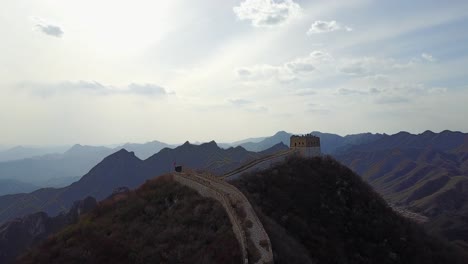 Aerial-descends-to-mountain-summit-guard-tower,-Great-Wall-of-China