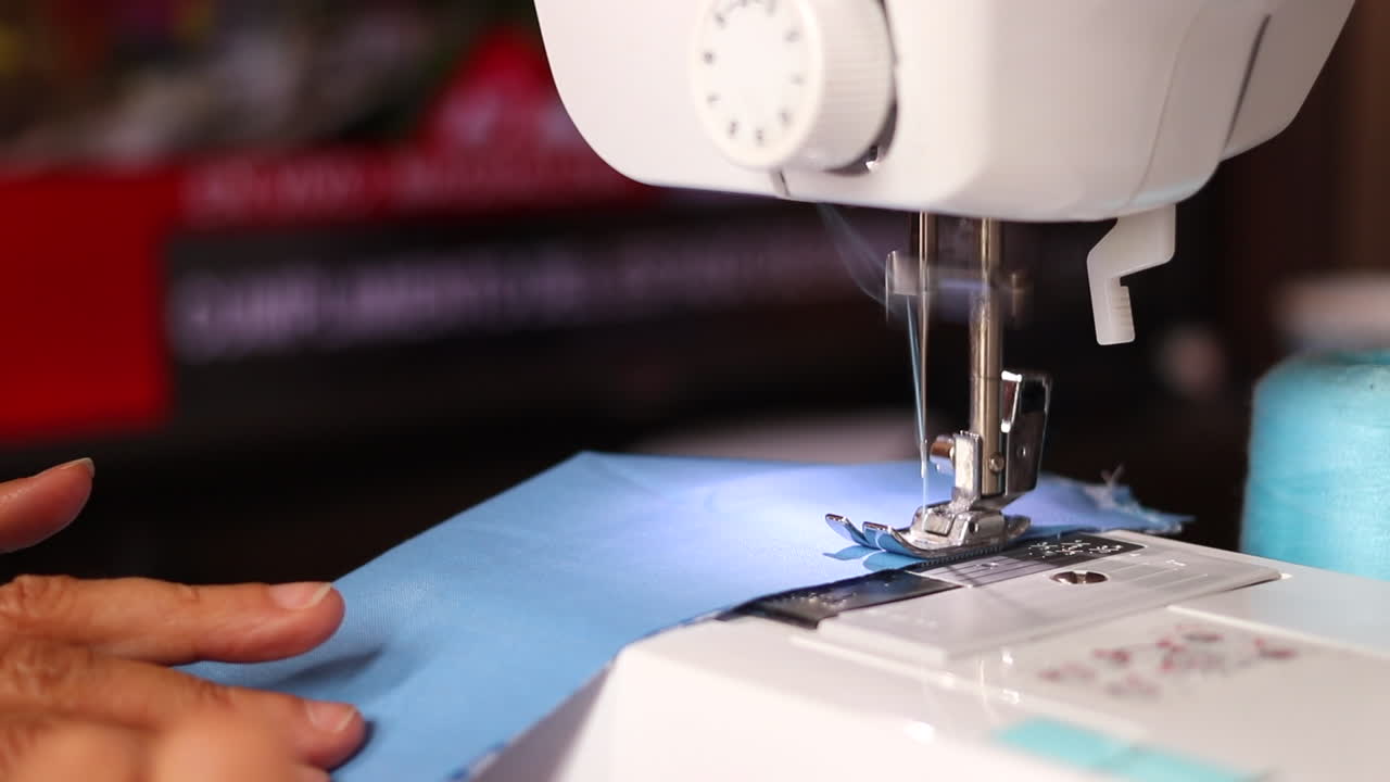 Close-up of Hands Sewing Blue Fabric on a Sewing Machine