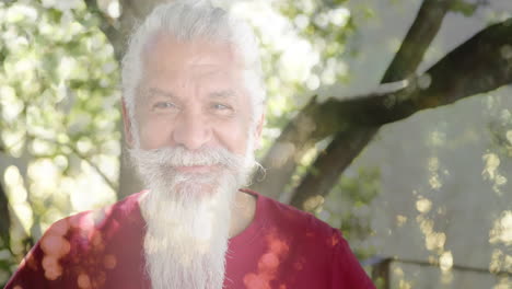 Animación-De-Puntos-De-Luz-Y-árboles-Sobre-Un-Hombre-Birracial-Senior-Sonriente-En-El-Jardín