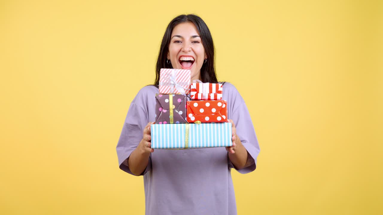 Happy Woman Holding a Stack of Presents on a Yellow Background
