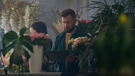 Florista-Masculino-Cuenta-Flores-En-Un-Jarrón-Y-Toma-El-Orden-Usando-Una-Tableta