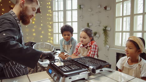 chef teaching kids how to cook waffles on culinary class