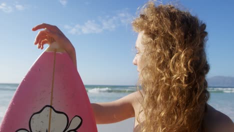 female surfer standing with surfboard at beach 4k