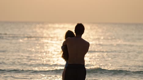 a loving pair stands barefoot on the soft white sands of dhigurah as the sun sinks toward the horizon.