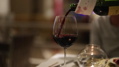 a sequence of pouring red wine into a glass at a sophisticated dining setting, highlighting elegance and relaxation