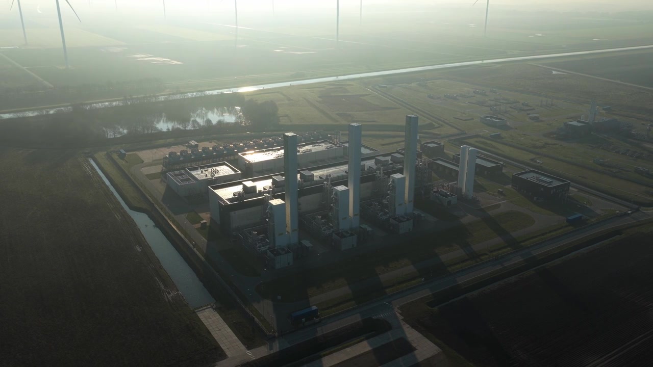Aerial view of the gasunie nitrogen plant in zuidbroek, netherlands, at sunrise with wind turbines visible through the morning mist