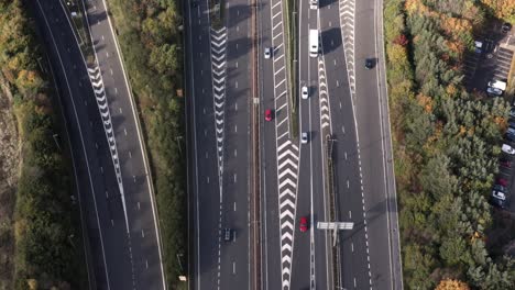 Helicopter-police-chase-style,-bird's-eye-view-of-a-busy-motorway,-following-a-high-speed-red-car-overtaking-other-cars-|-Edinburgh,-Scotland-|-4K-at-30fps