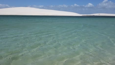 clear blue lagoon surrounded with white sand dunes