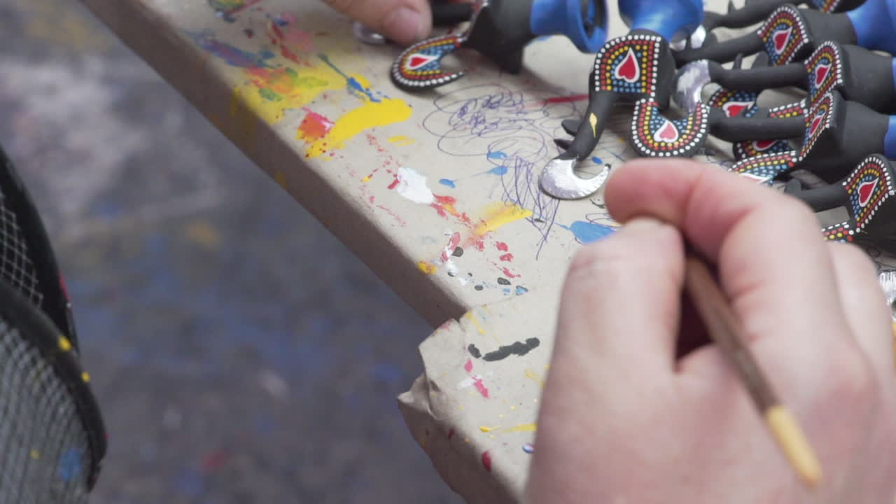 una vista cercana de una persona pintando un "gallo de barcelos", un conocido símbolo y recuerdo de portugal