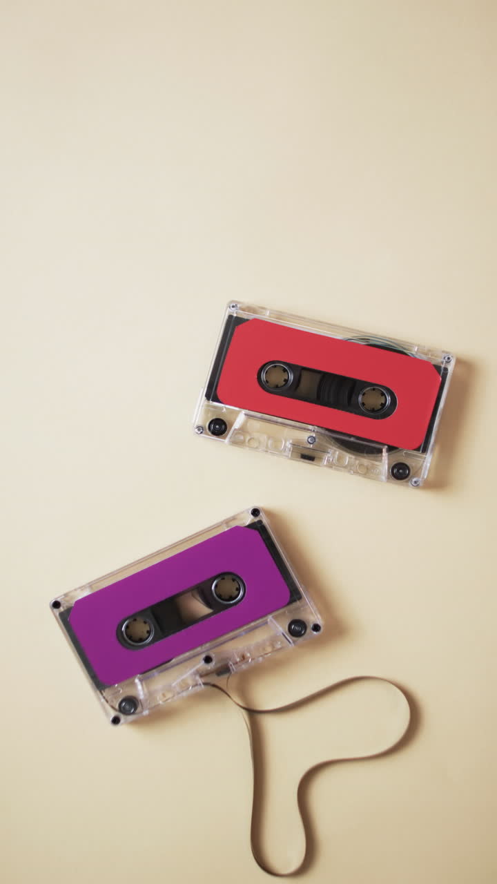 Vertical video of retro tapes with pink and red labels and copy space on yellow background