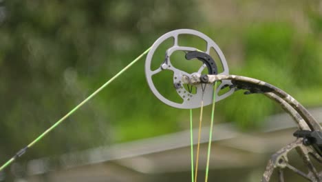 a slow motion shot of the top cam of a compound bow as the bow is drawn and released