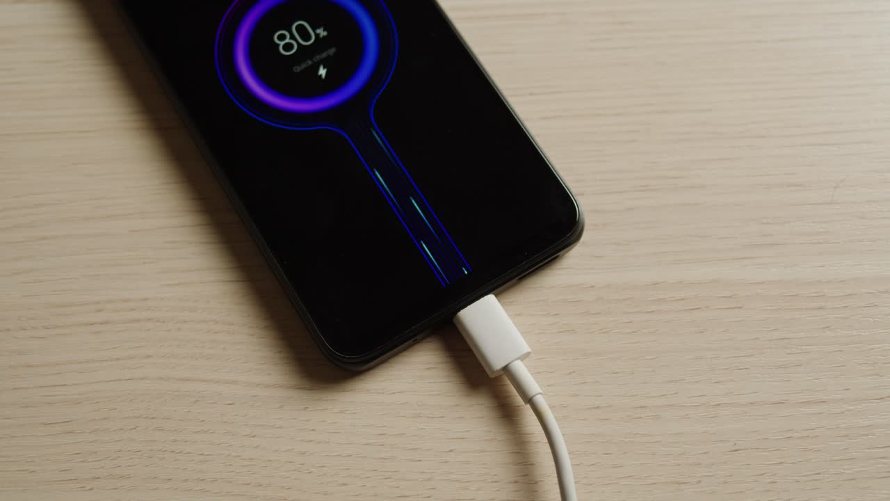 A closeup image depicts a smartphone connected to a charger, displaying an animated battery at 80 charge