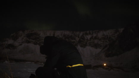 hombre solitario acampa en el fiordo nevado, medita bajo el cielo nocturno de la aurora, lofoten