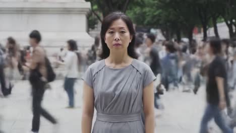 a solitary woman stands still amidst a bustling crowd, embodying the contrast between individuality and the relentless pace of urban life, highlighting moments of introspection in a busy world.