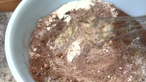 mezclar los ingredientes para un pastel de chocolate con un batidor, incluyendo harina, azúcar, cacao, levadura en polvo y bicarbonato de sodio