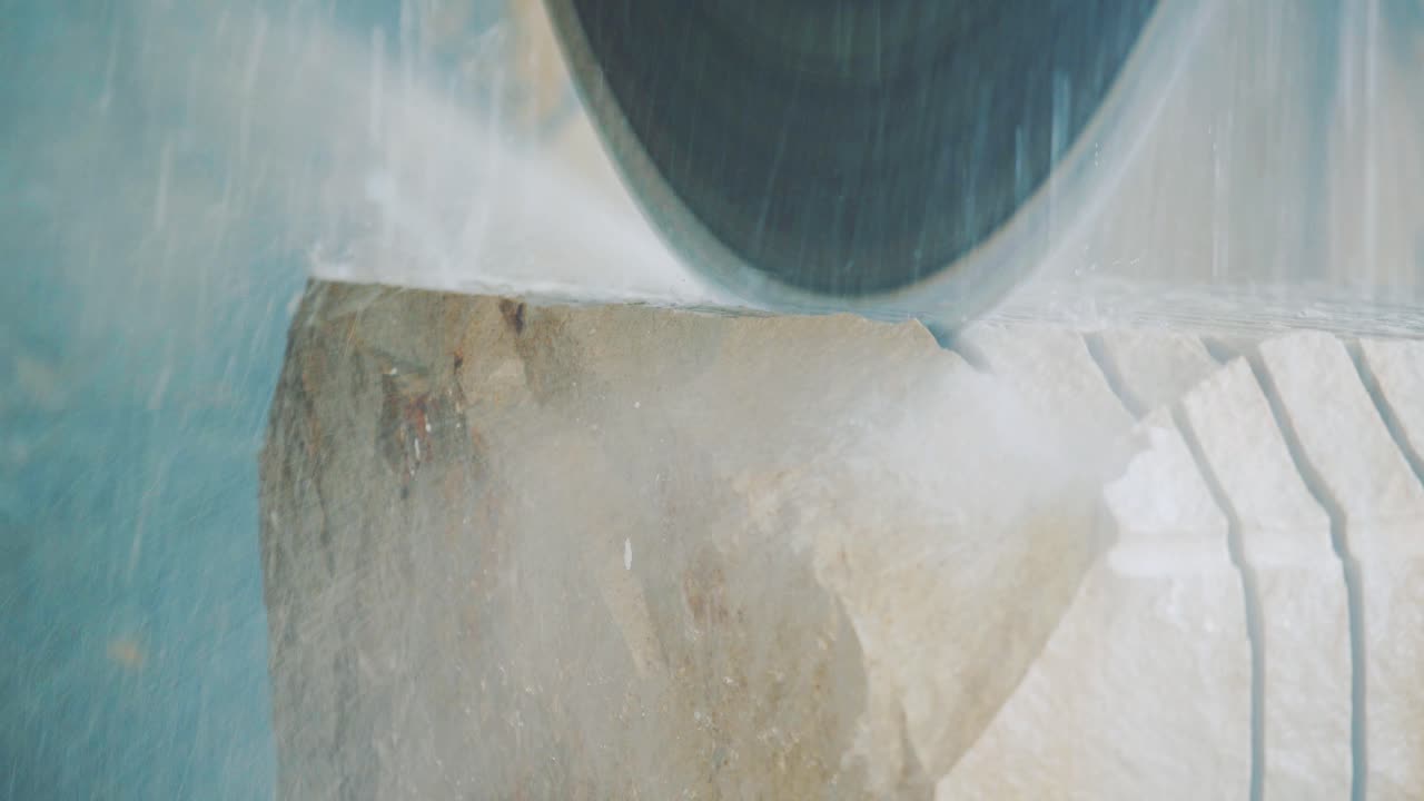 Circular saw cuts a large stone into small plates. Electric saw with water at the factory