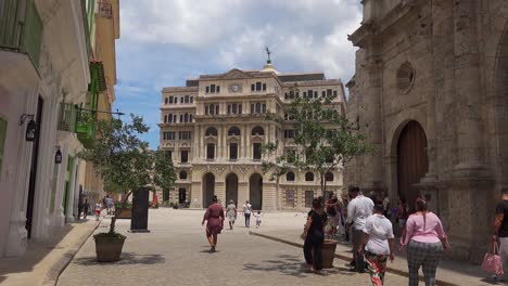 building of edificio de la lonja del comercio de la habana (produce exchange building) from oficios street in cuba, tourists walking