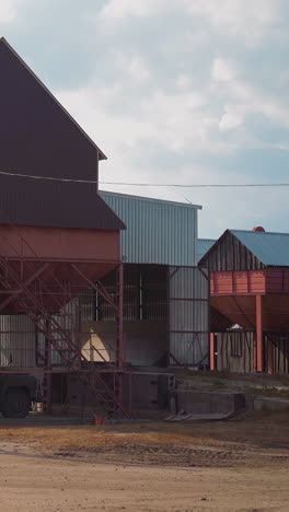 loading grains into truck body from funnel near granary building at countryside. wheat harvest transportation and sorting process. agricultural industry