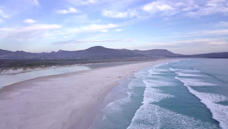 Aerial-footage-of-the-beach-in-Noordhoek,-South-Africa-panning-down-to-the-water