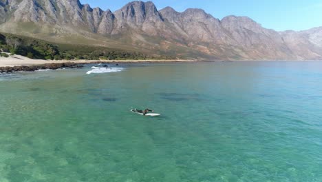 a man paddling out to sea on his surfboard in clear waters on a bright summer day