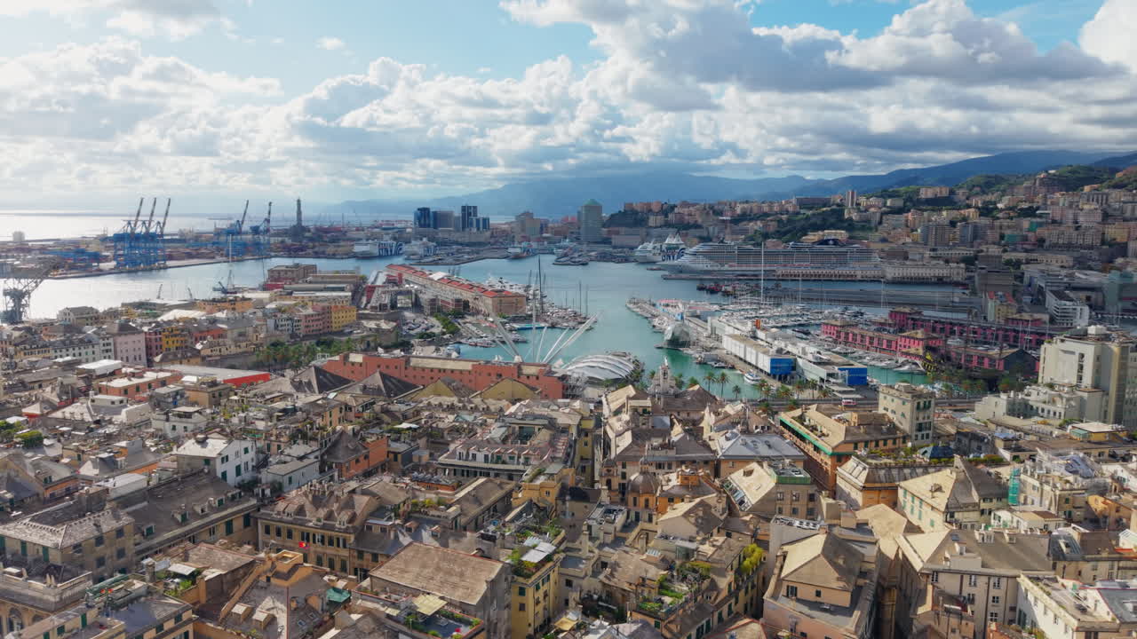 Drone flying backward over Genoa’s historic center, revealing the port, ships, and maritime buildings under a sunny sky with clouds