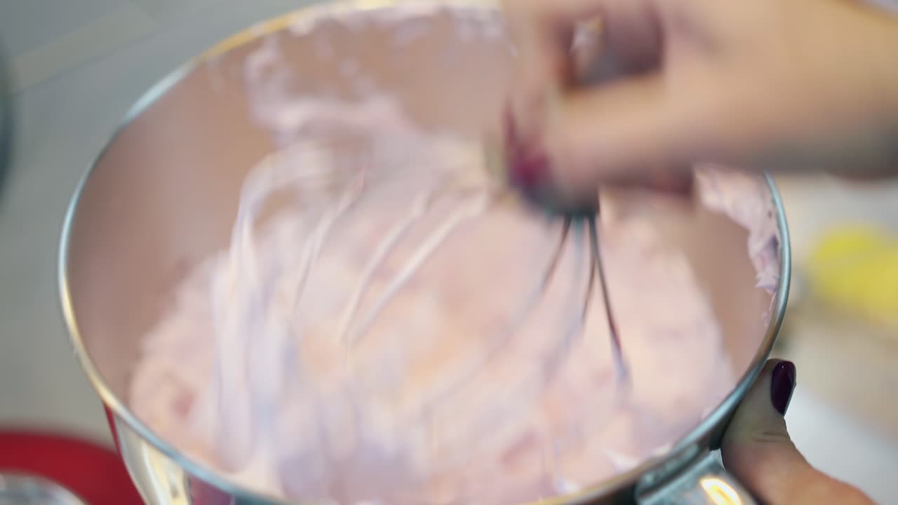 donna dimostra crema di torta spessa rosa in una ciotola di metallo