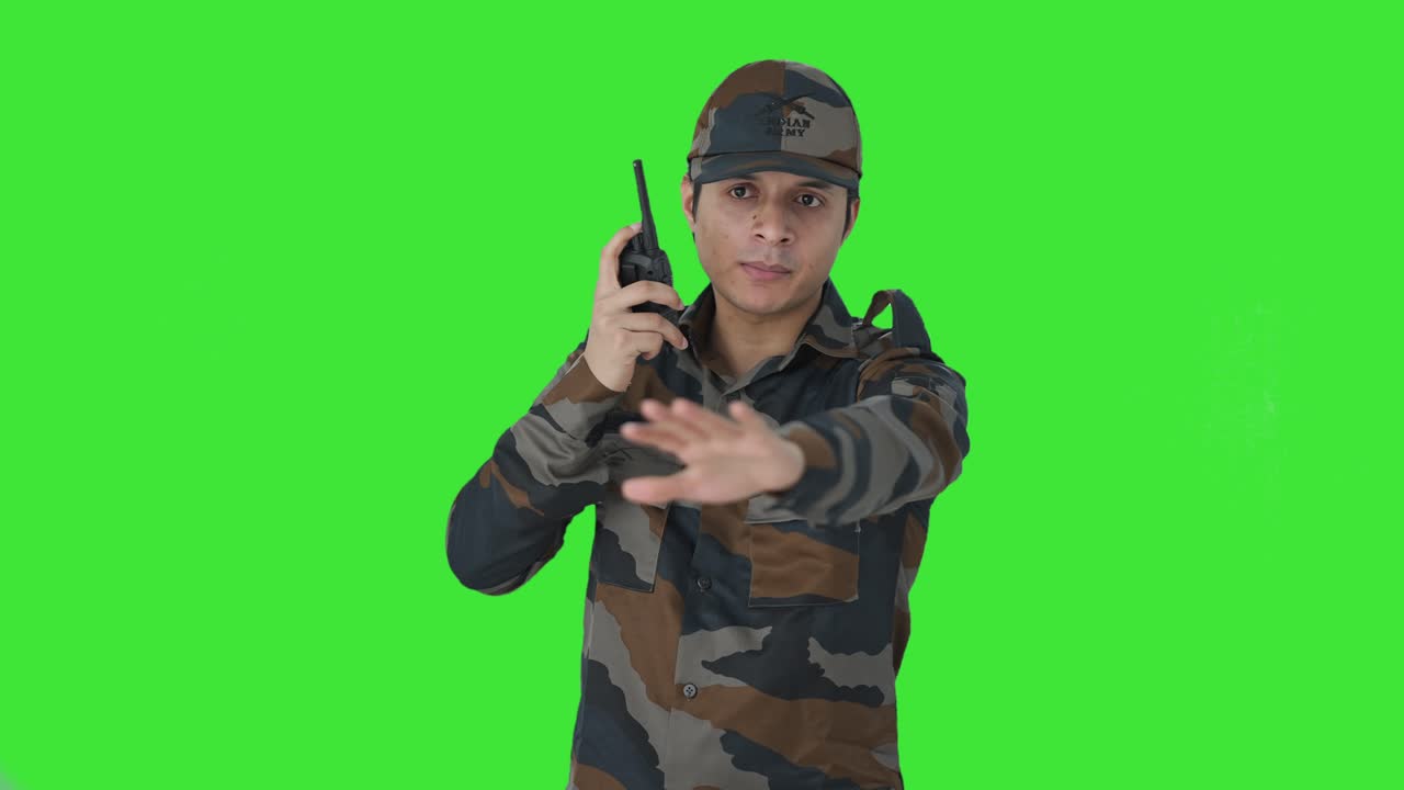 Uomo dell'esercito indiano che dà istruzioni con un walkie-talkie, schermo verde
