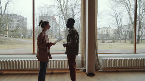 multiethnic man and woman discussing papers in modern hall