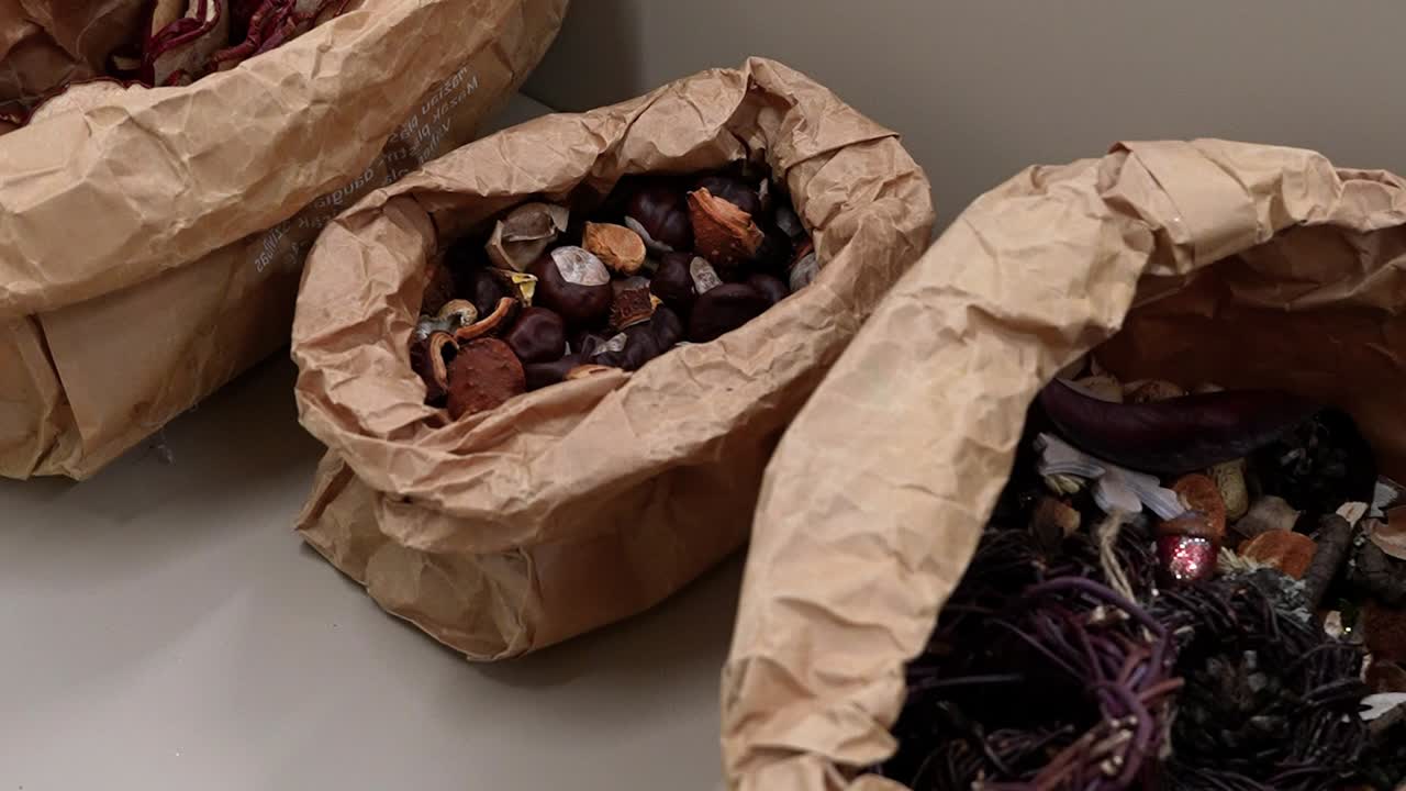 Detailed view of Advent wreath decorations with pinecones and dried pods in rustic paper bags. Natural textures and warm tones create a cozy, festive atmosphere. Perfect for holiday themes