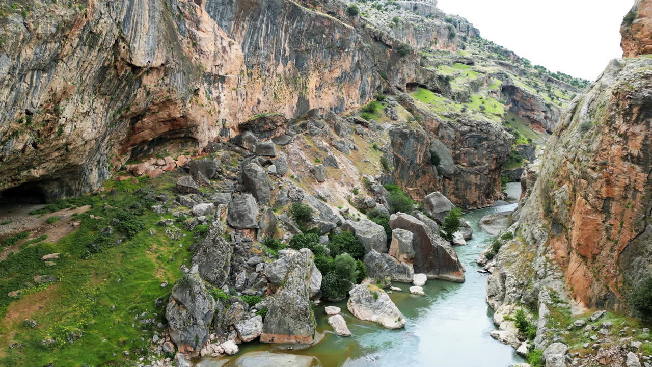 Dronebilde gjennom en steinete canyon med bratte klipper og en flytende elv nedenfor, som fanger det robuste naturlandskapet i den historiske Mesopotamia-regionen.
