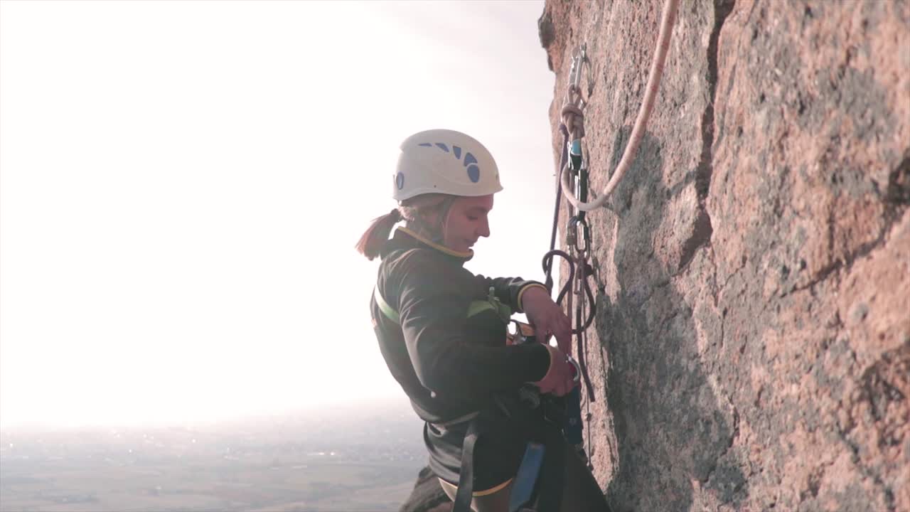 escalador femenino colgando de cuerdas en una roca vertical