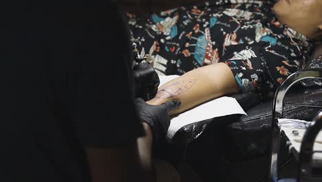 tattoo artist applying tattoo on man's arm