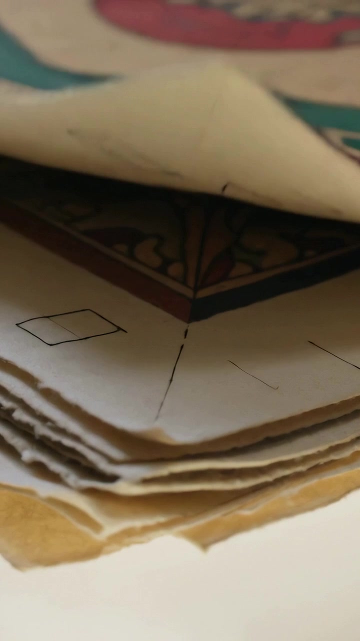 Vertical video: Lifting top sheet and moving camera, deckled stack on desk revealing corner motif