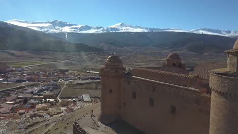 Aerial-view-of-the-castle-of-La-Calahorra-with-Sierra-Nevada-behind-in-Granada,-Spain