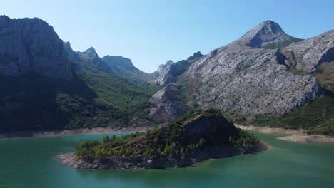 Captura-Aérea-Con-Drones-Girando-En-Una-Pequeña-Isla-En-El-Lago-Riaño-En-España