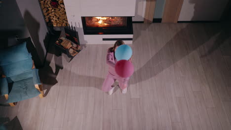 woman jumping with balloons in front of fireplace