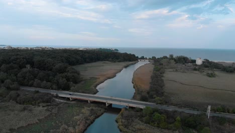 toma aérea del flujo del río hacia el mar y el puente del automóvil sobre el río
