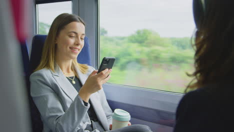 Geschäftsfrau-Mit-Kaffee-Zum-Mitnehmen-Auf-Dem-Weg-Zur-Arbeit-Im-Zug-Und-Blick-Auf-Ihr-Mobiltelefon