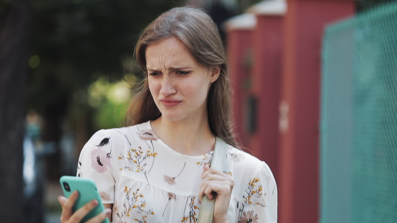 Young Woman Reacts with Disgust While Looking at Her Smartphone