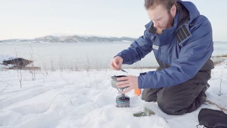 camper making herbal pine needle tea using portable stove