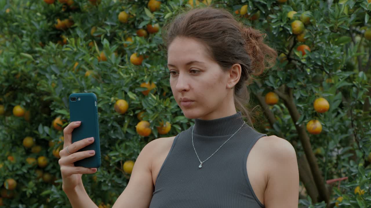 Woman taking a selfie in an orange orchard
