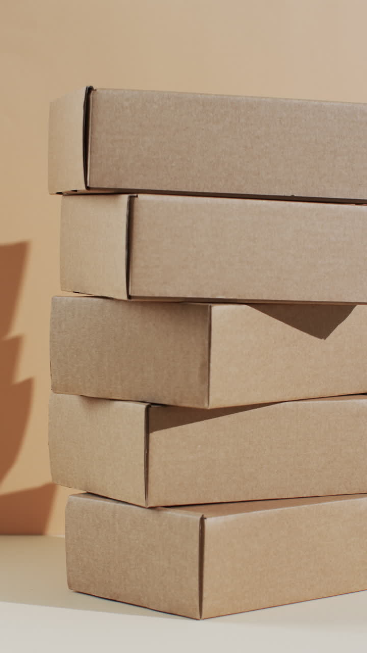 Vertical video of stacked cardboard boxes with copy space over brown background