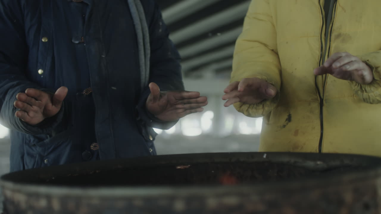 Homeless men warming hands under a bridge