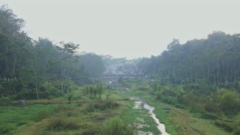 Fliegen-Sie-über-Den-Wasserfluss-Mit-Dem-Watu-Purbo-Wasserfall-Oder-„Grjogan-Watu-Purbo“-Im-Hintergrund-–-Geringe-Höhe