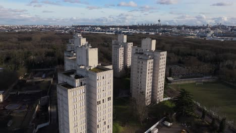 quartier fort d'aubervilliers, towering residential high-rises, green spaces, paris skyline in distance, france. aerial drone orbiting